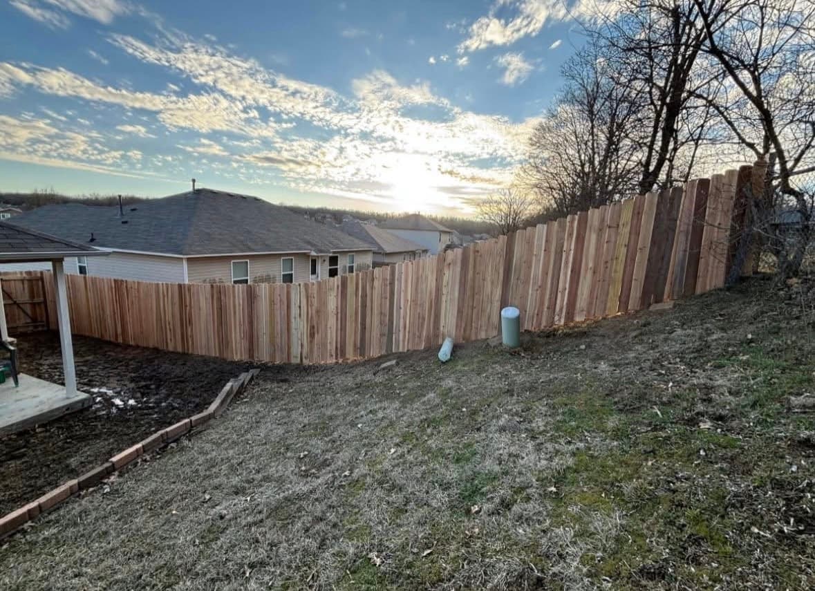New 6-foot dog-ear wood privacy fence along a sloped backyard in Sapulpa, Oklahoma, after professional installation